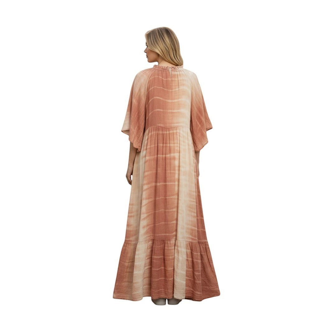 Woman wearing a flowing, tiered boho maxi dress in earthy tones with a tie-dye pattern and ruffled neckline.
