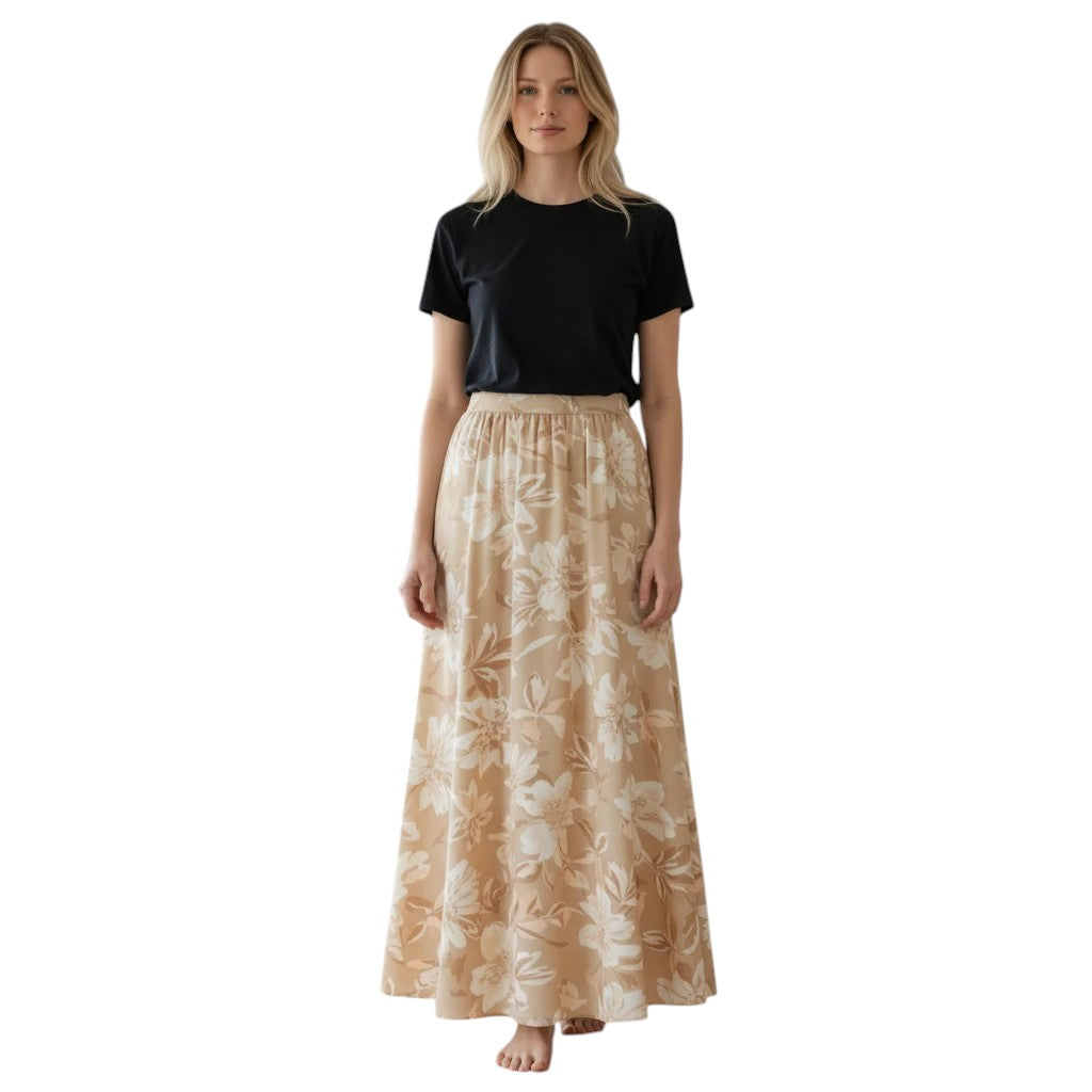 Flowing beige maxi skirt with a large white floral print and elastic waistband, worn by a blonde woman in a black t-shirt.