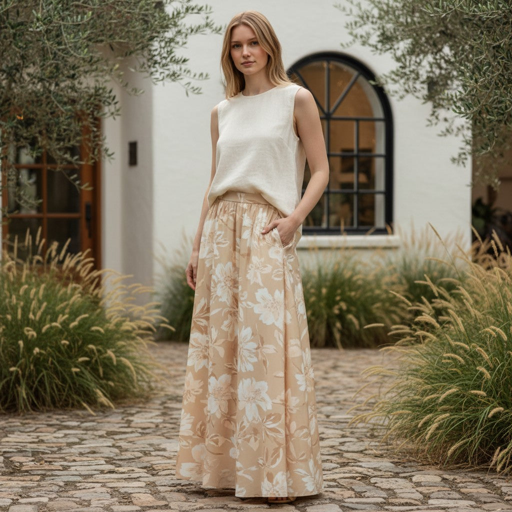 Beige A-line midi skirt with a large floral print in white and light brown, featuring an elastic waistband and flowing silhouette.