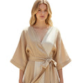 Woman wearing a beige and cream striped linen wrap midi dress with a V-neckline and self-tie belt.