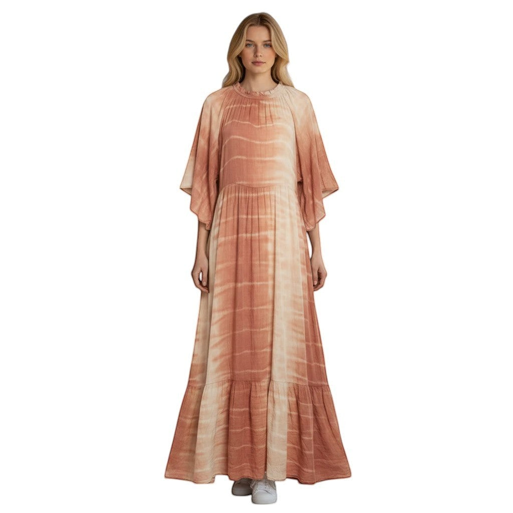 Woman wearing a tiered maxi dress with a tie-dye print in warm earth tones, featuring flowy sleeves and a ruffled hem.