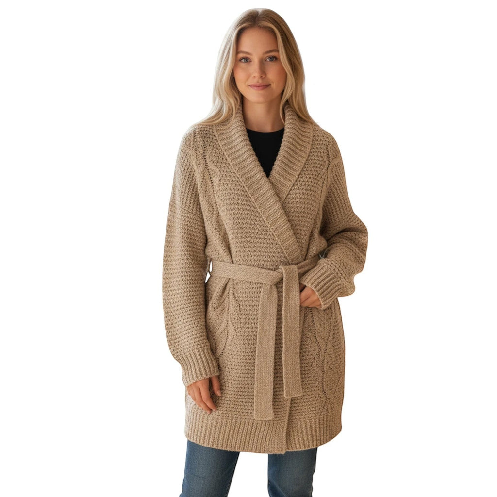 Woman wearing a beige cable knit belted cardigan sweater with a shawl collar and long sleeves.